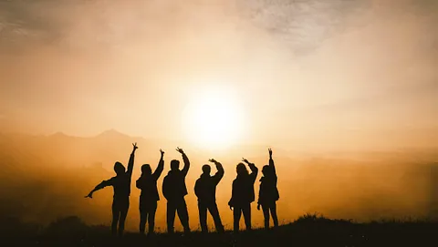 Silhuetter af mennesker ved solnedgang